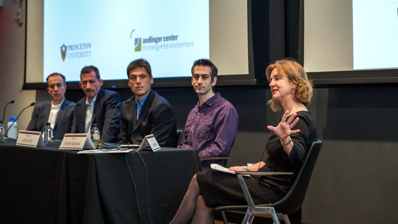Faculty member, seated at end of row of colleagues, leads panel discussion.