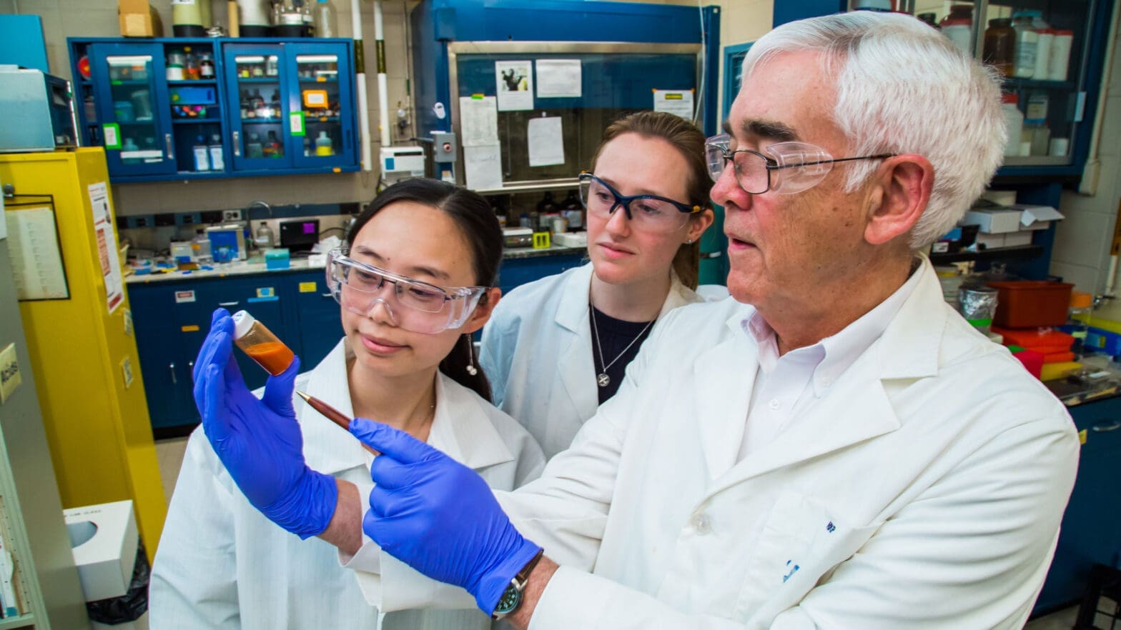 Three researchers work with lab equipment