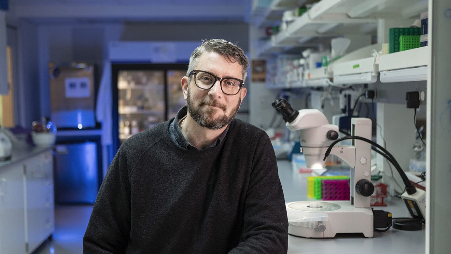 Portrait of researcher in lab near microscope.