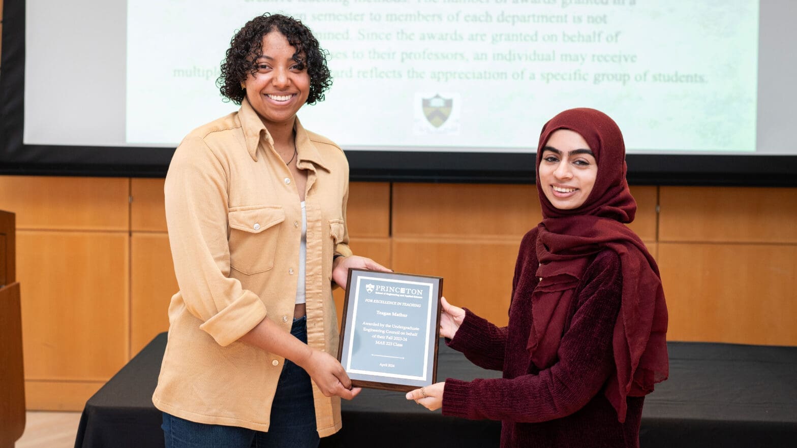 Two women hold an award plaque at the ceremony